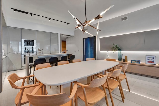 dining room featuring light tile flooring, rail lighting, and an inviting chandelier