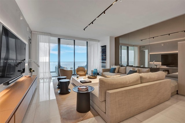 living room with expansive windows, a water view, light tile floors, and track lighting