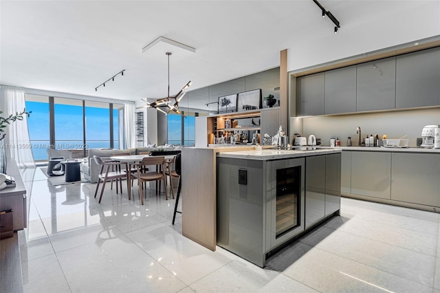 kitchen with a center island, light tile flooring, a breakfast bar, rail lighting, and gray cabinetry