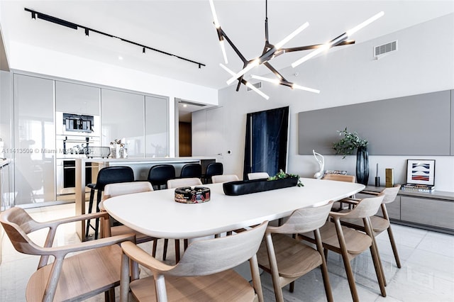 tiled dining area featuring an inviting chandelier and track lighting