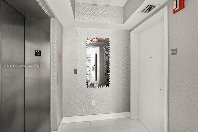 hallway with light tile floors and elevator