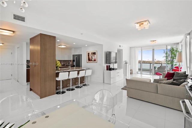 tiled living room featuring a water view and sink