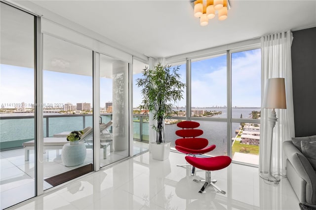 interior space with floor to ceiling windows, a water view, a chandelier, and multiple windows