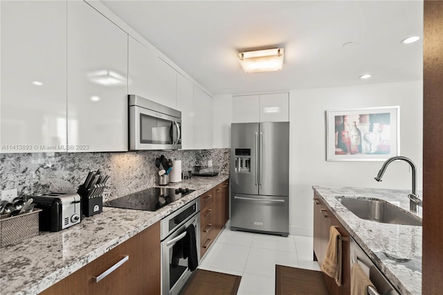 kitchen with backsplash, stainless steel appliances, white cabinetry, and sink