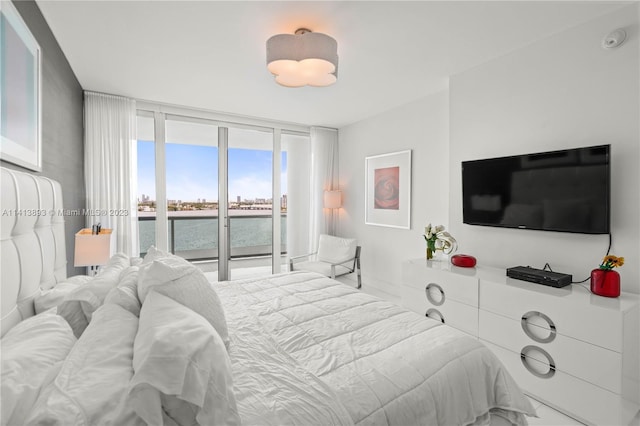 bedroom with access to outside, a wall of windows, and a water view