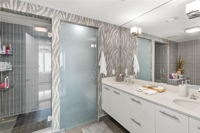 bathroom with tile floors, dual bowl vanity, and a shower with door