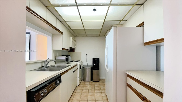 kitchen with sink, white cabinets, a paneled ceiling, and stainless steel appliances