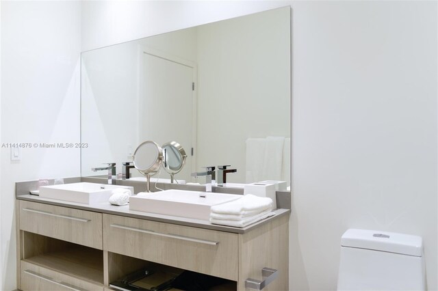 bathroom featuring toilet, double sink, and oversized vanity