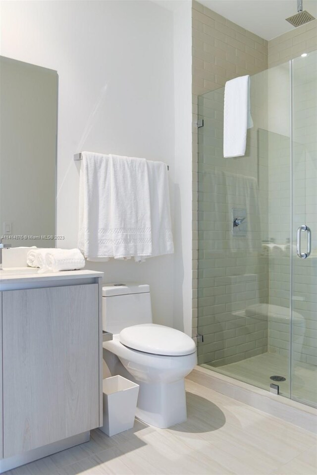 bathroom featuring an enclosed shower, toilet, vanity, and tile floors