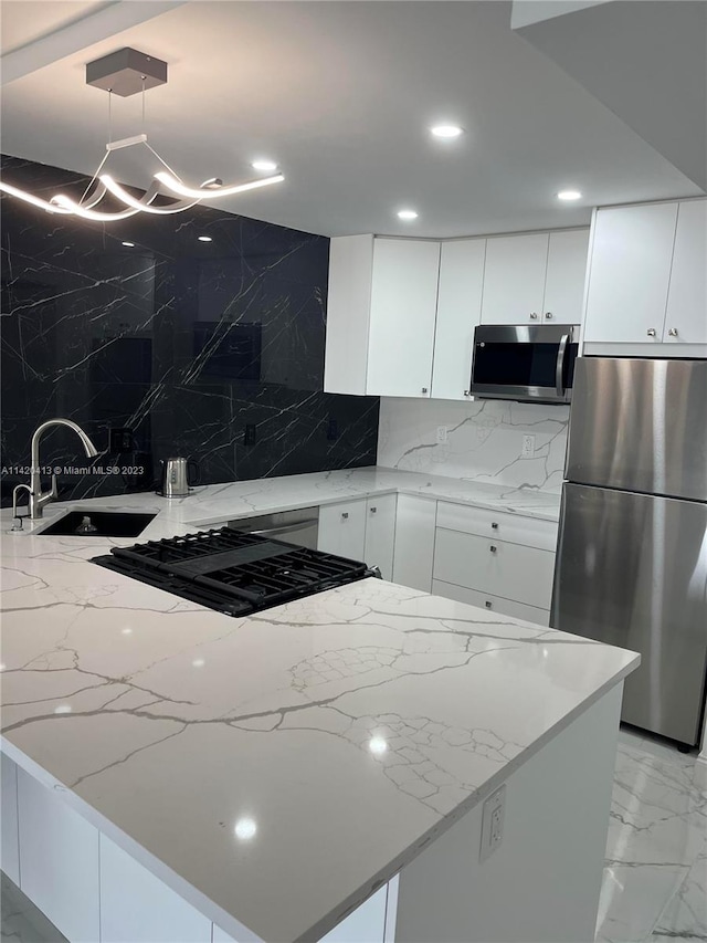 kitchen featuring backsplash, sink, stainless steel appliances, white cabinets, and pendant lighting