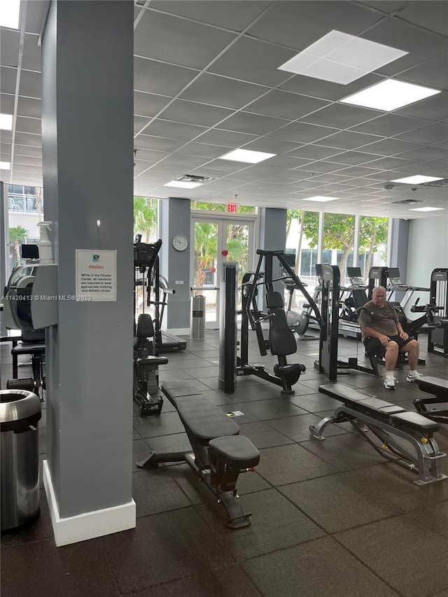 exercise room featuring plenty of natural light, floor to ceiling windows, and a drop ceiling