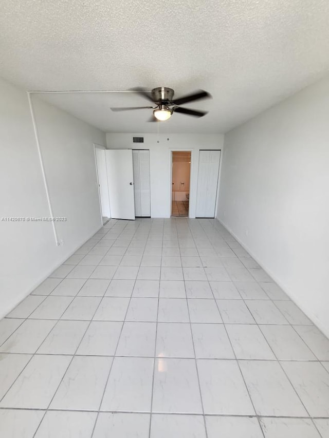 unfurnished bedroom featuring ceiling fan, light tile floors, and a textured ceiling