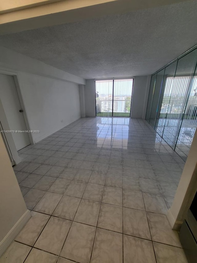 tiled empty room with a textured ceiling and expansive windows