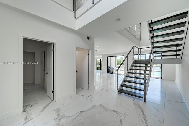 stairway with a towering ceiling and light tile floors