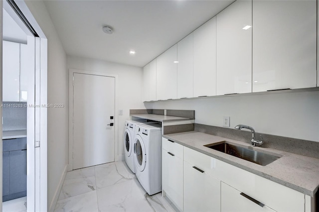 laundry room with sink, washing machine and clothes dryer, light tile flooring, and cabinets