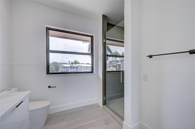 bathroom featuring a shower with door, hardwood / wood-style flooring, toilet, and vanity