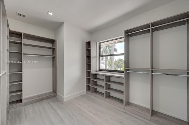 walk in closet with light hardwood / wood-style floors