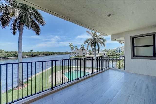 balcony featuring a fenced in pool and a water view