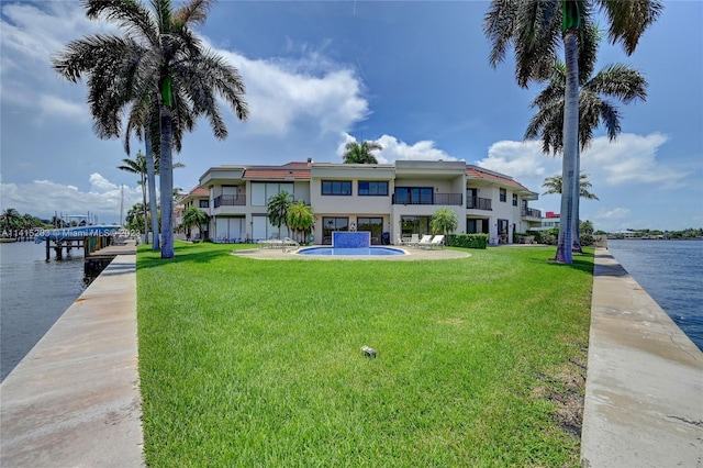 view of dock featuring a balcony, a lawn, and a water view