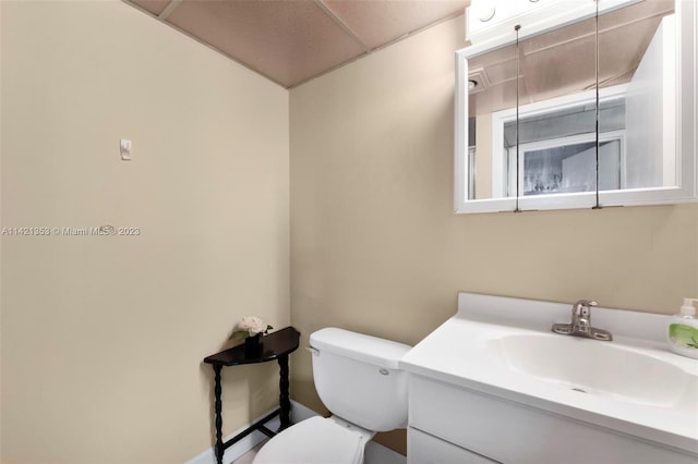 bathroom featuring a drop ceiling, large vanity, and toilet