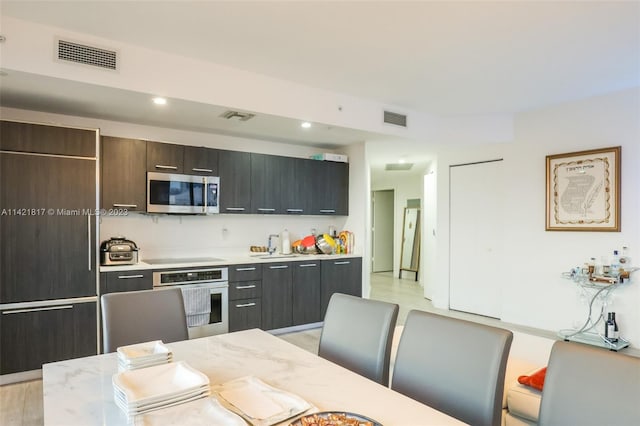 kitchen with light hardwood / wood-style floors, light stone countertops, and stainless steel appliances