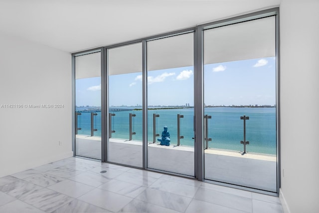 tiled spare room with a water view and a wall of windows