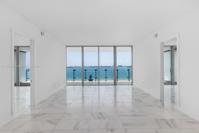 tiled spare room with a water view and a wall of windows