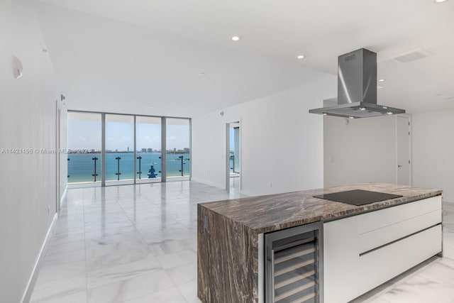 kitchen with floor to ceiling windows, white cabinets, beverage cooler, stovetop, and extractor fan