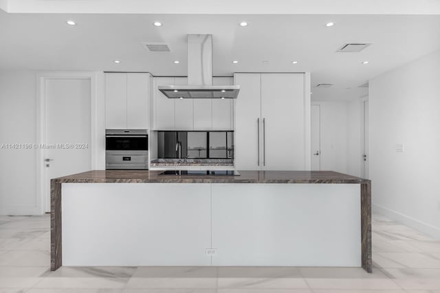 kitchen with white cabinetry, light tile patterned floors, a center island, appliances with stainless steel finishes, and island exhaust hood