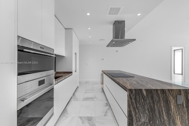 kitchen with island exhaust hood, stainless steel double oven, and white cabinets