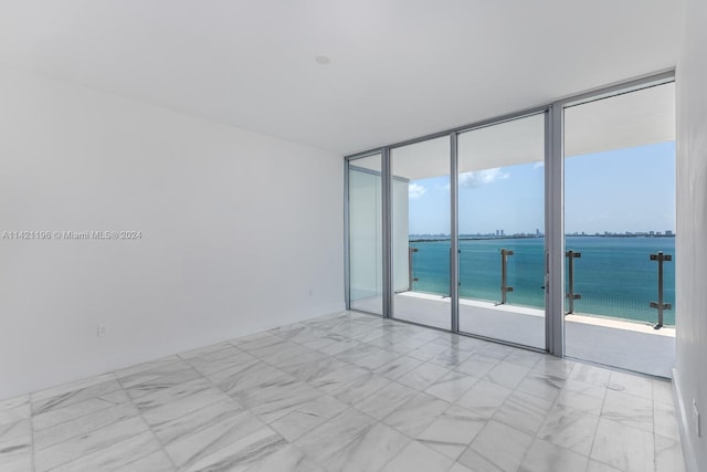 tiled spare room featuring a water view and expansive windows