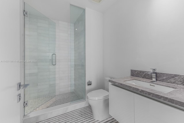 bathroom featuring a shower with shower door, vanity, tile patterned floors, and toilet