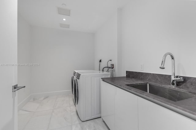 clothes washing area with light tile patterned flooring, cabinets, washing machine and dryer, and sink