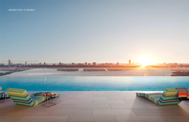 pool at dusk with a patio area