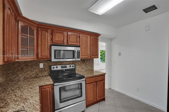 kitchen with stone counters, tasteful backsplash, stainless steel appliances, and light tile floors