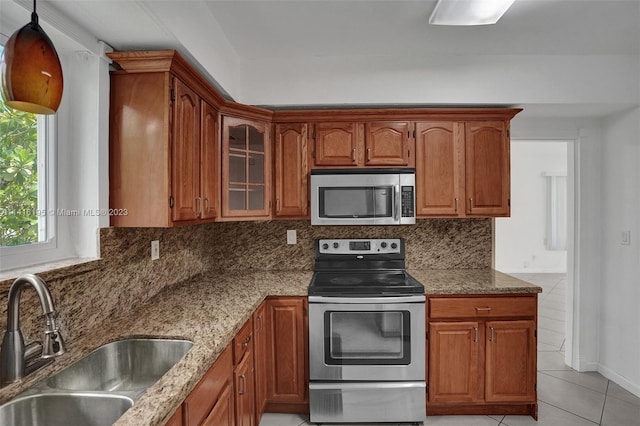 kitchen with stone counters, tasteful backsplash, stainless steel appliances, and sink