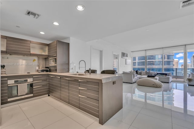 kitchen with stainless steel appliances, sink, light tile floors, and a wall of windows