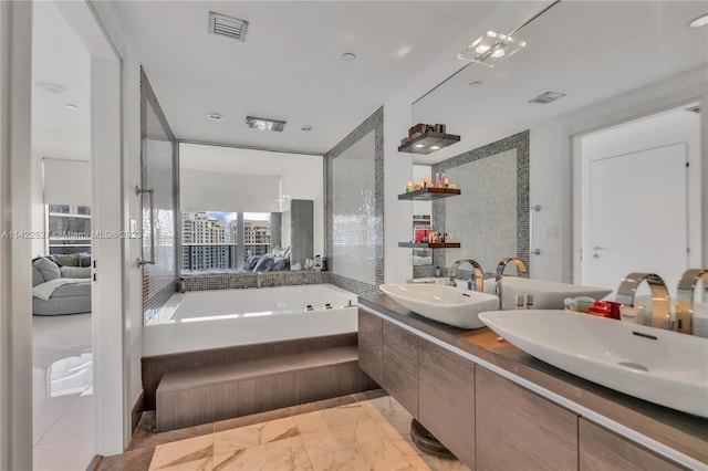 bathroom with double vanity, tiled tub, and tile floors