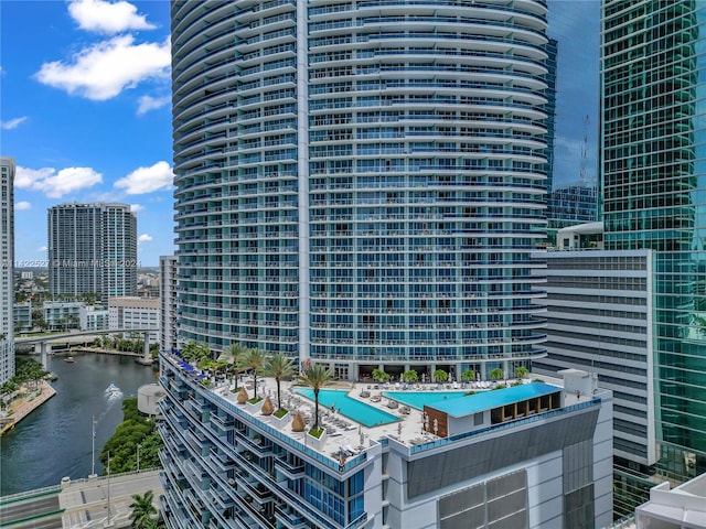 view of building exterior featuring a community pool and a water view