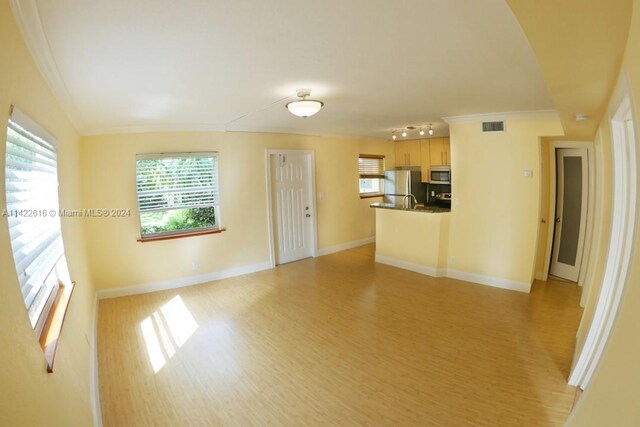 interior space featuring rail lighting, crown molding, a healthy amount of sunlight, and light hardwood / wood-style flooring