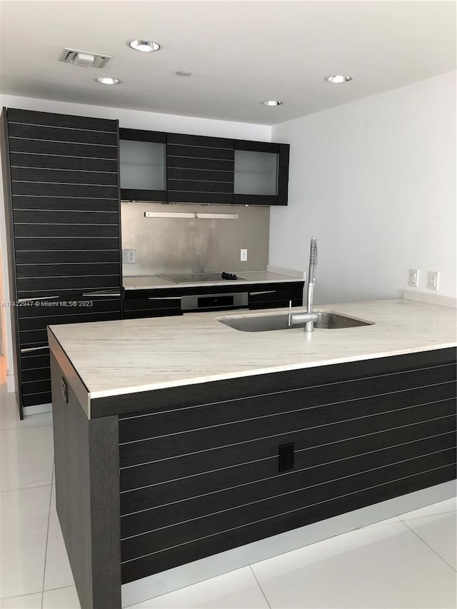 kitchen with black electric stovetop, sink, and light tile floors