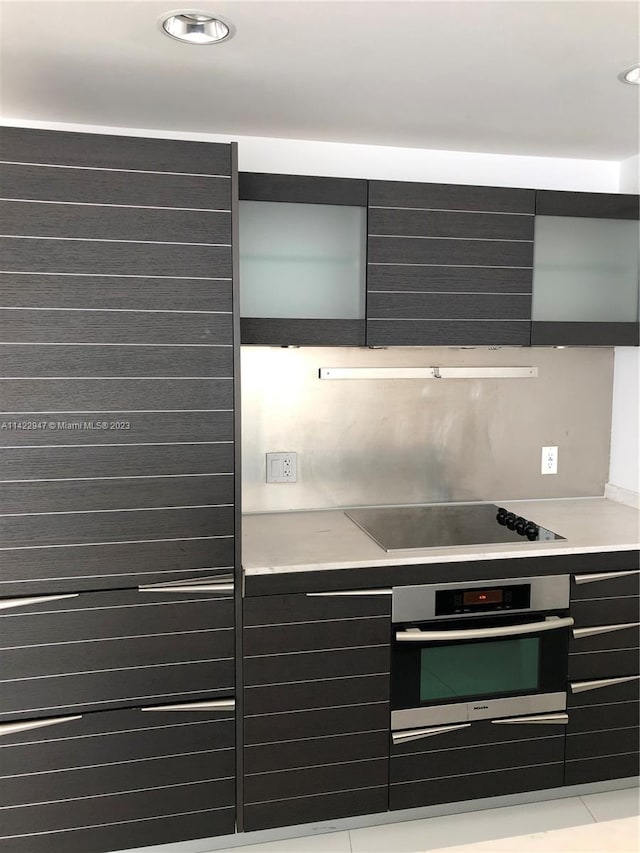 kitchen featuring black electric stovetop, stainless steel oven, and exhaust hood