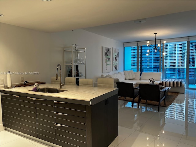 kitchen featuring a chandelier, light tile floors, decorative light fixtures, a wall of windows, and sink