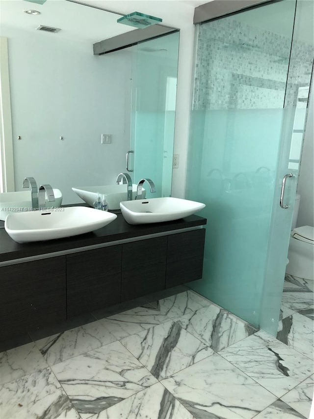 bathroom featuring an enclosed shower, dual sinks, tile flooring, toilet, and oversized vanity