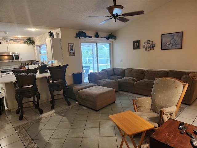 living room with light tile patterned flooring, a textured ceiling, ceiling fan, and vaulted ceiling