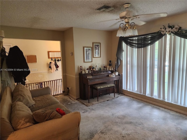 living room featuring a textured ceiling, ceiling fan, and concrete floors