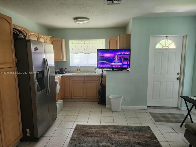 kitchen with light tile patterned floors, sink, stainless steel refrigerator with ice dispenser, and a textured ceiling