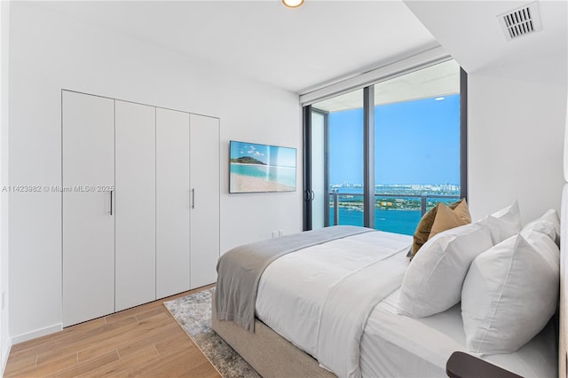 bedroom with a closet, a wall of windows, and light hardwood / wood-style flooring