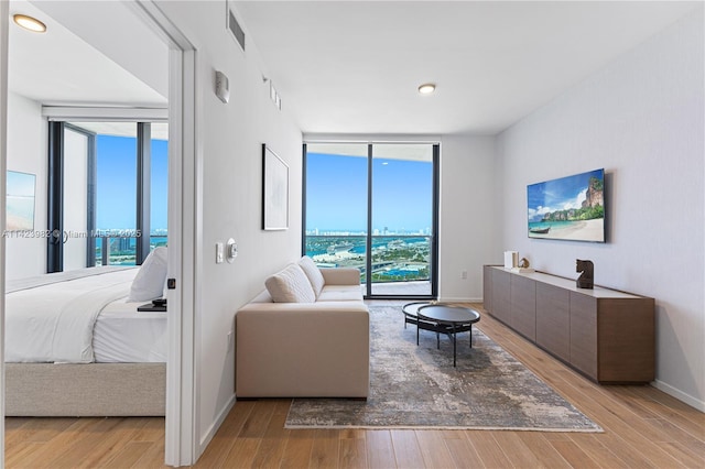 bedroom featuring access to outside, a wall of windows, and light wood-type flooring