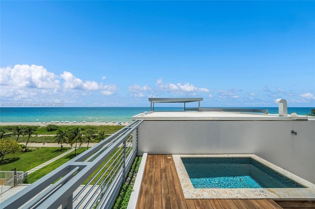 view of swimming pool featuring a water view, an outdoor hot tub, and a view of the beach